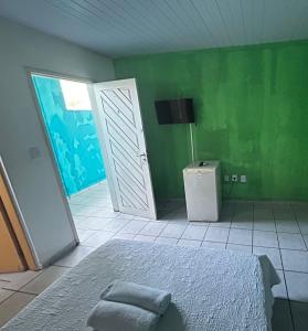 a bedroom with a bed and a green wall at Pipa Hotel Pe na Areia in Pipa