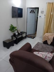 a living room with a couch and a flat screen tv at Cozy Escape 876 Secure 2BR with AC, Parking & near Beaches in Portmore
