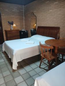 a bedroom with a large bed and a wooden table at Aluguel de suítes praia do frances in Marechal Deodoro