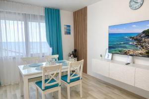 a dining room with a table and chairs and a tv at Apartment Sea Sunrise, complex Carpe Diem, FREE PARKING in Balchik