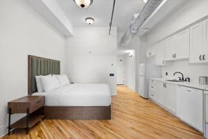 a white bedroom with a bed and a kitchen at Tri Century Mill Suites in Carleton Place +67 photos