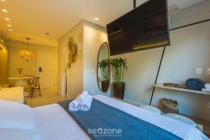 a bedroom with a bed with a tv and a table at Studio in center of Rosa, rooftop w/ pool RSO0031 in Imbituba