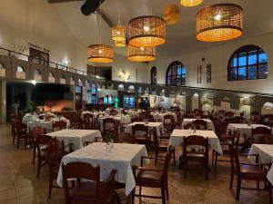 a dining room with white tables and chairs and chandeliers at Tenondé Park Hotel in São Miguel das Missões