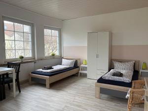 a bedroom with two beds and a table and chairs at Monteurwohnungen Am Deich - Ideal für Langzeitaufenthalte in ruhiger Lage in Bremerhaven