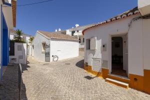 a cobblestone alley with white buildings and a doorway at A27 - Caracol Corner Studio in Lagos in Lagos