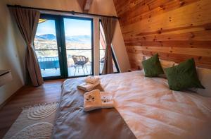 a bedroom with a large bed with a large window at Royal Hill Bran-A-Frame and Bungalows whit Hot Tub and Sauna in Sohodol