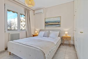 a white bedroom with a bed and two windows at Fabulous central apartment close to the sea! in Chalkida