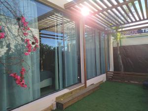 a screened in porch with glass windows and pink flowers at Casita acristalada con jacuzzi in Tiñosa Alta