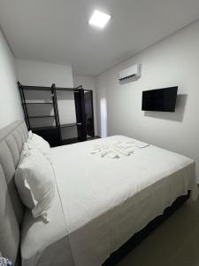 a bedroom with a bed with white sheets and a tv at Gran Reserva Maragogi in Maragogi +22 photos