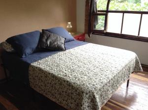 a bedroom with a bed with a blanket and a window at Casa Cafetal Coatepec in Coatepec