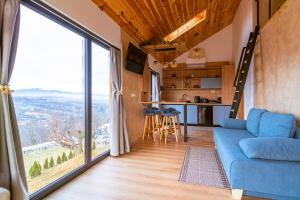 a living room with a blue couch and a large window at Royal Hill Bran-A-Frame and Bungalows whit Hot Tub and Sauna in Sohodol