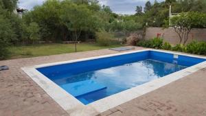a swimming pool in a backyard with blue water at Los Aromos Cabañas loft in San Marcos Sierras