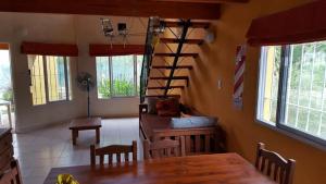 a dining room with a table and a spiral staircase at Los Aromos Cabañas loft in San Marcos Sierras