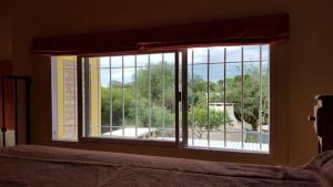 a bedroom window with a view of a yard at Los Aromos Cabañas loft in San Marcos Sierras +1 photo