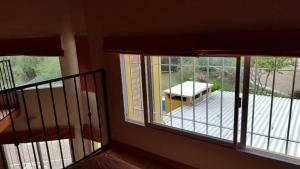 a room with two windows and a balcony with a table at Los Aromos Cabañas loft in San Marcos Sierras