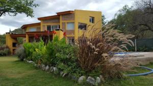 a yellow house with a garden in front of it at Los Aromos Cabañas loft in San Marcos Sierras