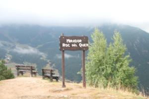 a sign on the top of a mountain with two benches at Casa Rural Restaurant Borda Patxeta in Canillo