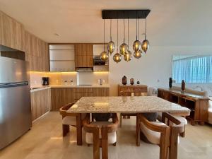 a kitchen with a table with chairs and a refrigerator at Zantamar 105B, a pie de playa in Cruz de Huanacaxtle