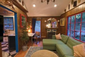 a living room with a green couch and a fireplace at Vintage Lovers` Cabin with Jacuzzi & Lake Access in Linden