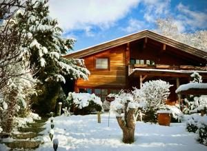 a log cabin in the snow with snow covered trees at Landhaus de Gaspary in Seehausen am Staffelsee
