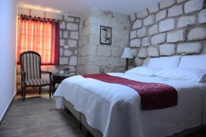 a bedroom with a large bed and a stone wall at Mensa Christi Guesthouse in Nazareth