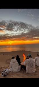 a group of people sitting on the beach watching the sunset at Surf home Appartement in Taghazout