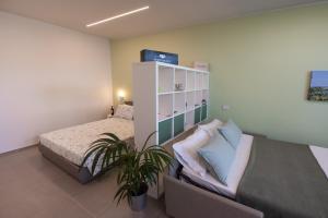 a bedroom with two beds and a plant in it at Al Ventisei - Verde in Treiso