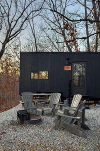 a black tiny house with two chairs and a table at Postcard Cabins St Francois, Outdoor Collection by Marriott Bonvoy in Bloomsdale