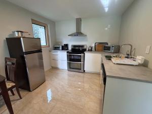 a kitchen with a stainless steel refrigerator and white cabinets at Coastal Drift Sooke in Sooke