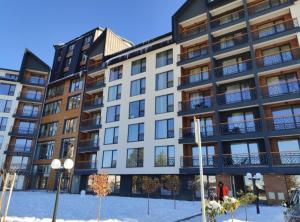 an apartment building with snow in front of it at Yellow Hill Apartment in Cajetina