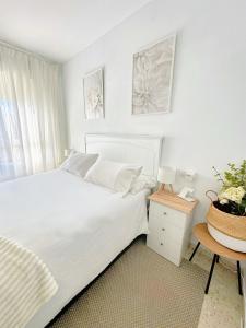 a white bedroom with a bed and a table at Limon Home in Benacazón