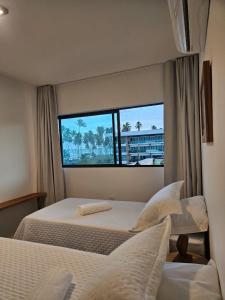 a bedroom with two beds and a large window at Apartamento Ipioca Beach Life in Ipioca +27 photos
