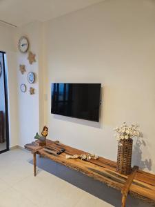 a living room with a table and a television on a wall at Apartamento Ipioca Beach Life in Ipioca