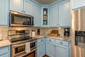 a kitchen with blue cabinets and stainless steel appliances at Lavender Haze - 1209 Chaumont in Dauphin Island