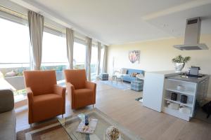 a living room with two chairs and a kitchen with windows at Luxury apartment near trade fair in Düsseldorf