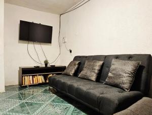 a black couch in a living room with a tv at Casa del Parque en Toluca in Toluca