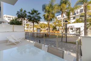 a balcony with a table and chairs and palm trees at RentitSpain - Playa Granada - Apartamentos TRM Aguacate Relax entre Mar, Golf y Montaña in Motril