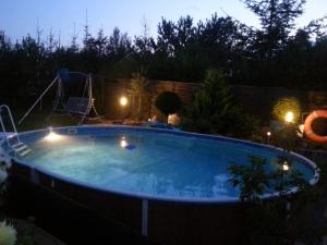 a large swimming pool in a backyard at night at Dom pod flagą in Sobącz