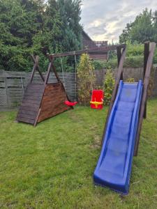 a playground with a blue slide and a red chair at Dom pod flagą in Sobącz