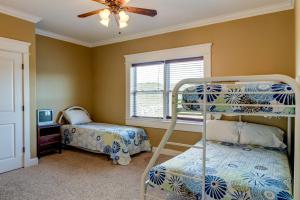 a bedroom with two bunk beds and a ceiling fan at Purple Parrot - 200 Lenora Ct in Dauphin Island