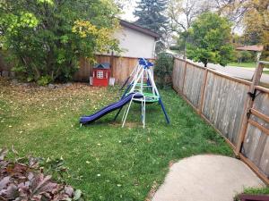 a blue slide in a yard next to a fence at 3 cozy bedrooms 2 bathrooms in Winnipeg