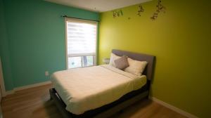 a bedroom with a bed with a green wall at 3 cozy bedrooms 2 bathrooms in Winnipeg