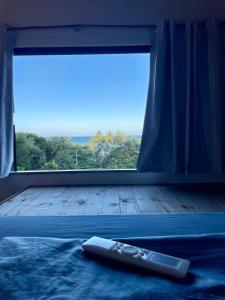 a remote control laying on a bed in front of a window at Pousada Leve Mar in Ilhéus