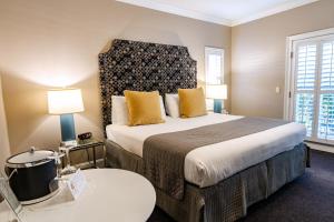 a hotel room with a large bed with yellow pillows at Bel Abri Napa Valley Inn in Napa