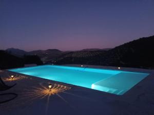a blue swimming pool at night with mountains in the background at Casa Laguna in Iznájar +19 photos