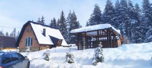 a building covered in snow with a car parked next to it at Vila Dunja Pale in Pale