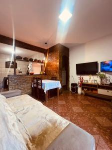 a room with a bed and a kitchen with a tv at Lar Doce Estadia in São Pedro da Aldeia