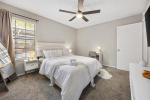 a white bedroom with a bed and a ceiling fan at Emerald Loft - Pool, Gym & Free Parking! in Dallas