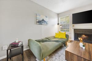 a living room with a green couch and a fireplace at Emerald Loft - Pool, Gym & Free Parking! in Dallas