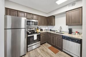 a kitchen with wooden cabinets and stainless steel appliances at Emerald Loft - Pool, Gym & Free Parking! in Dallas